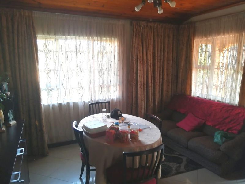 A living room featuring a timber ceiling, tiled flooring, and windows fitted with security bars.