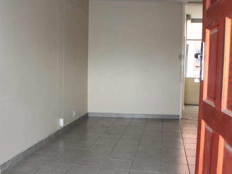 An empty living area featuring neutral wall paint and tiled flooring, providing a blank canvas for interior design and personalization.