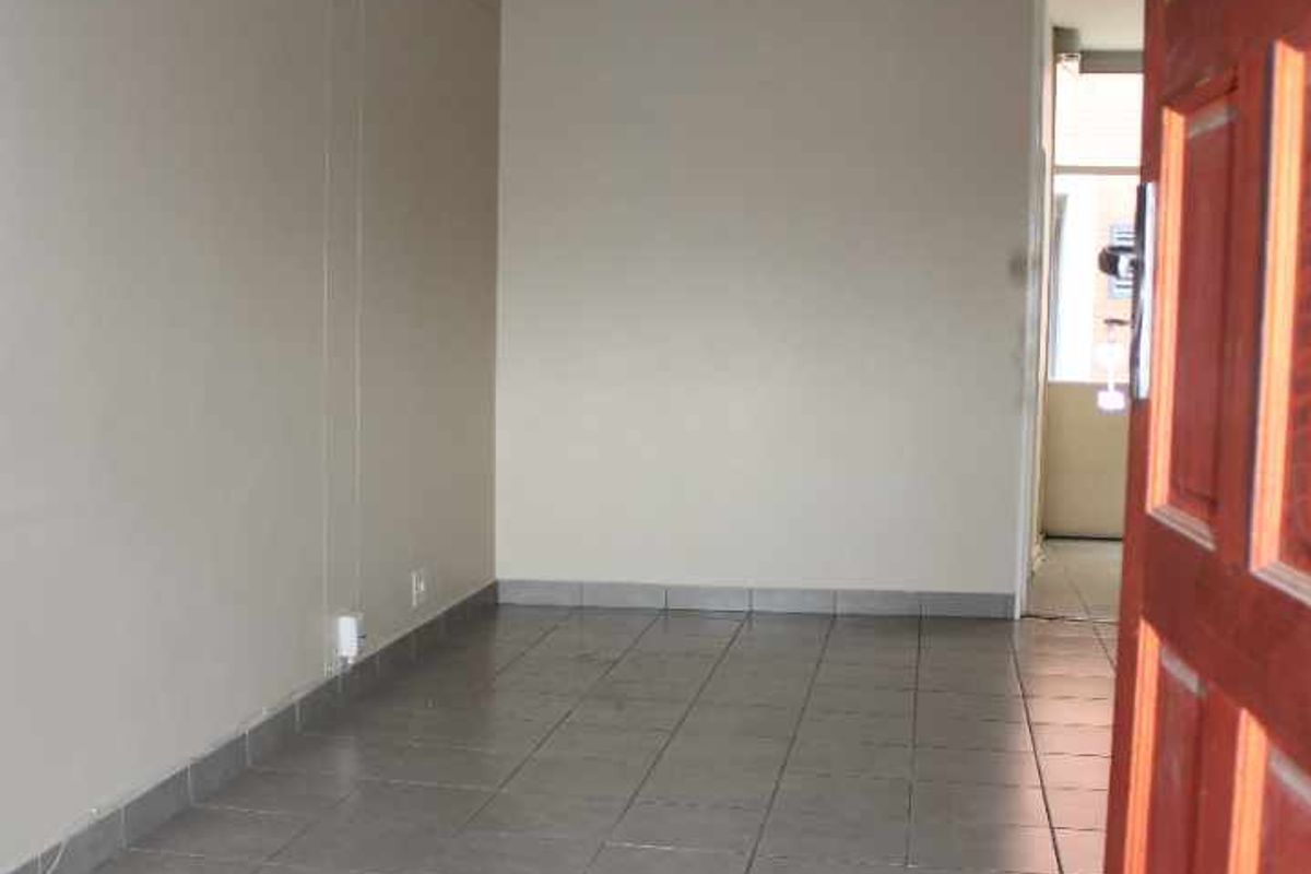 An empty living area featuring neutral wall paint and tiled flooring, providing a blank canvas for interior design and personalization.