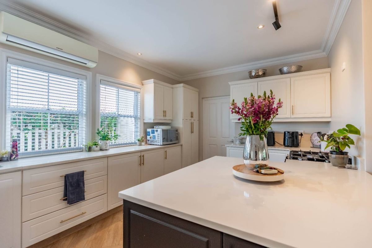 Modern kitchen featuring white cabinetry, stone countertops, a central island, gas cooktop, and split-system air conditioning with ample natural light.