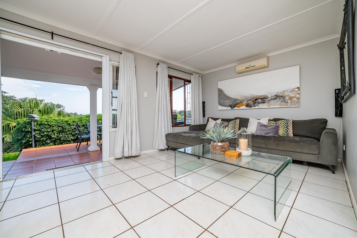 Bright living room featuring tiled flooring, split-system air conditioning, and direct access to a covered patio through sliding glass doors.