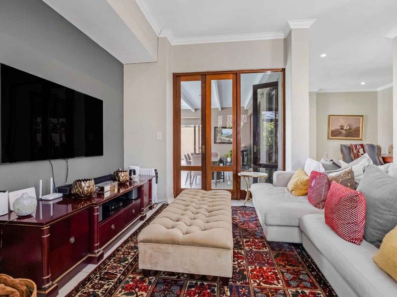 A well-maintained living room featuring an accent wall, recessed downlighting, and timber-framed glass doors providing access to the outdoor area.