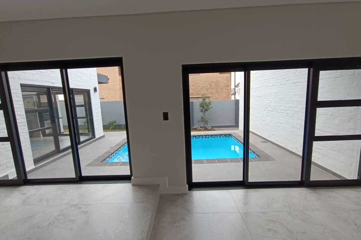 Interior view looking out through large sliding glass doors onto a private courtyard featuring a small swimming pool and paved patio area.