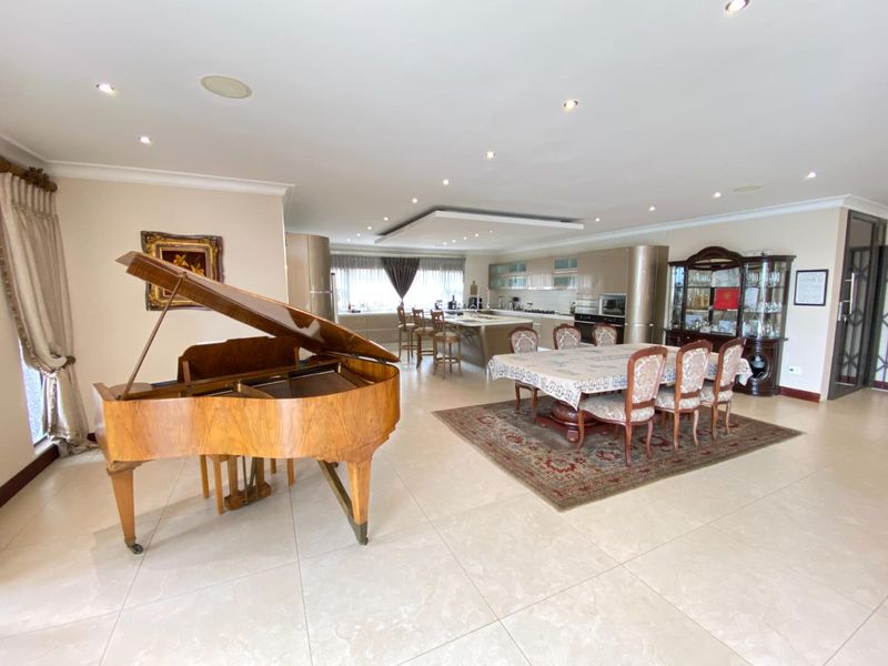 Spacious open-plan living area featuring a modern kitchen with island, tiled flooring, and recessed lighting, seamlessly connecting to the dining space.