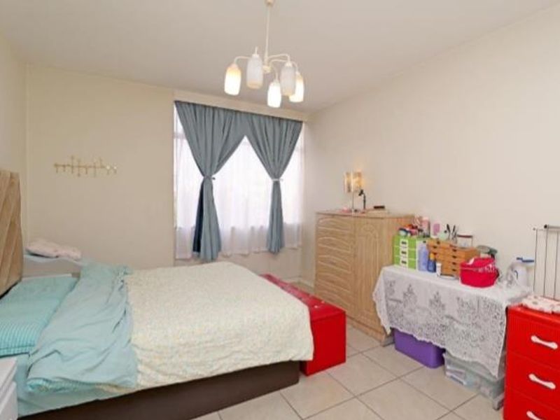 A functional bedroom featuring tiled flooring and a central ceiling light fixture, offering a neutral base for personalization.