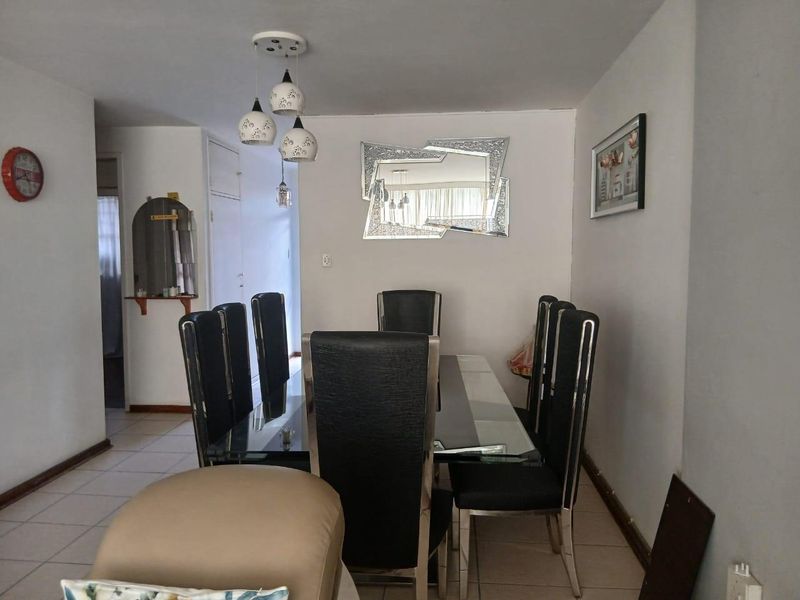 A functional dining area featuring tiled flooring, a decorative archway, and modern pendant lighting, providing a clear space for family meals.