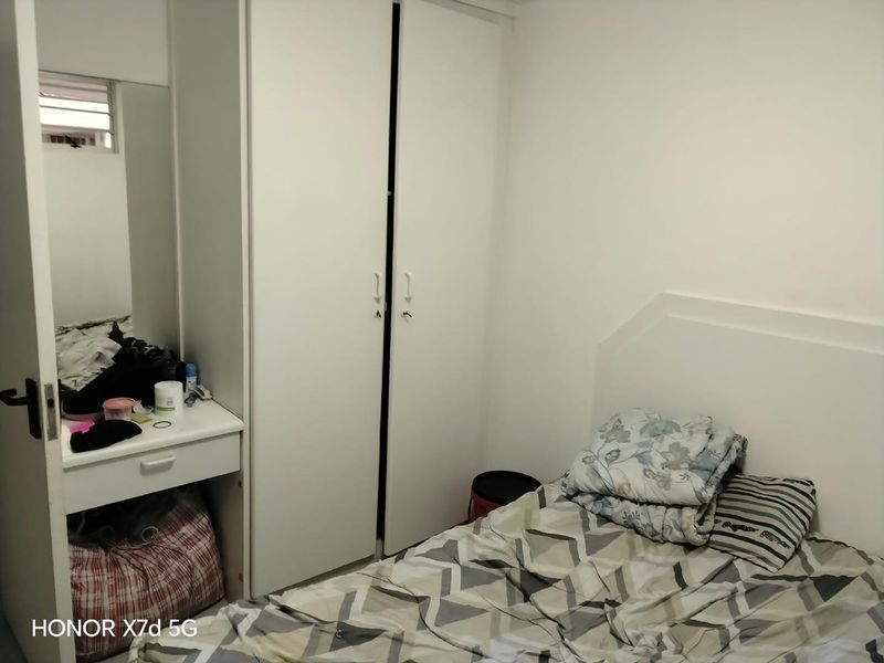 A compact bedroom featuring a built-in white wardrobe and integrated vanity unit with a mirror.