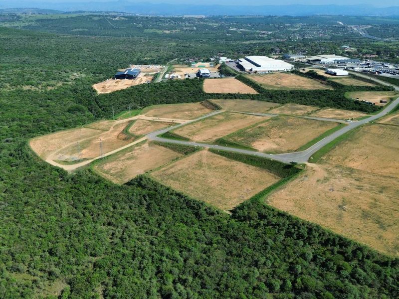 Aerial view of a large industrial development site featuring cleared land plots, paved access roads, and surrounding natural landscape.