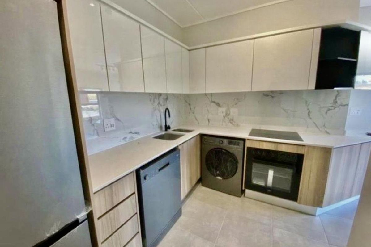 Modern kitchen featuring sleek white cabinetry, marble-look splashback, integrated oven, hob, and dedicated space for a dishwasher and washing machine.