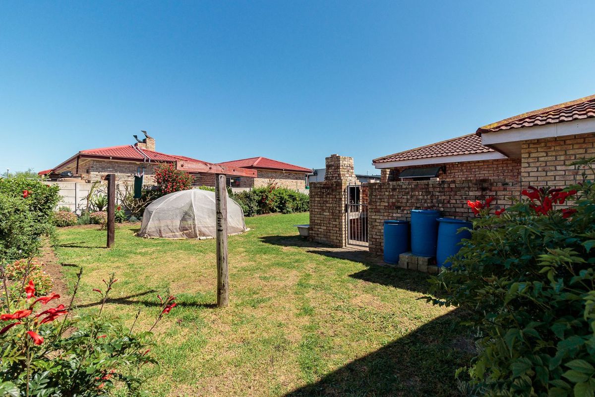 A private rear garden featuring a lawn, built-in brick braai area, and perimeter brick walling, offering a functional outdoor space.