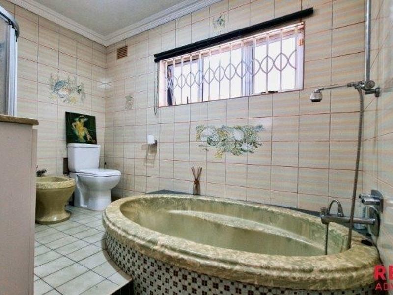 A dated bathroom featuring a built-in oval bathtub, separate shower enclosure, toilet, and bidet with tiled finishes throughout.
