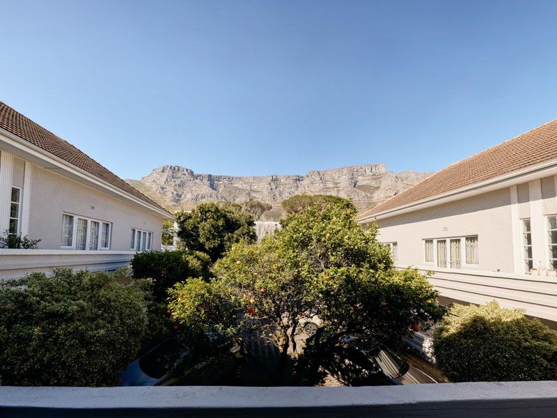 A scenic view of the surrounding apartment complex architecture with a prominent mountain backdrop and mature garden landscaping.