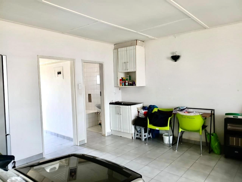 Open plan living area featuring tiled flooring, a small built-in kitchenette with cabinetry, and access to an adjacent bathroom.