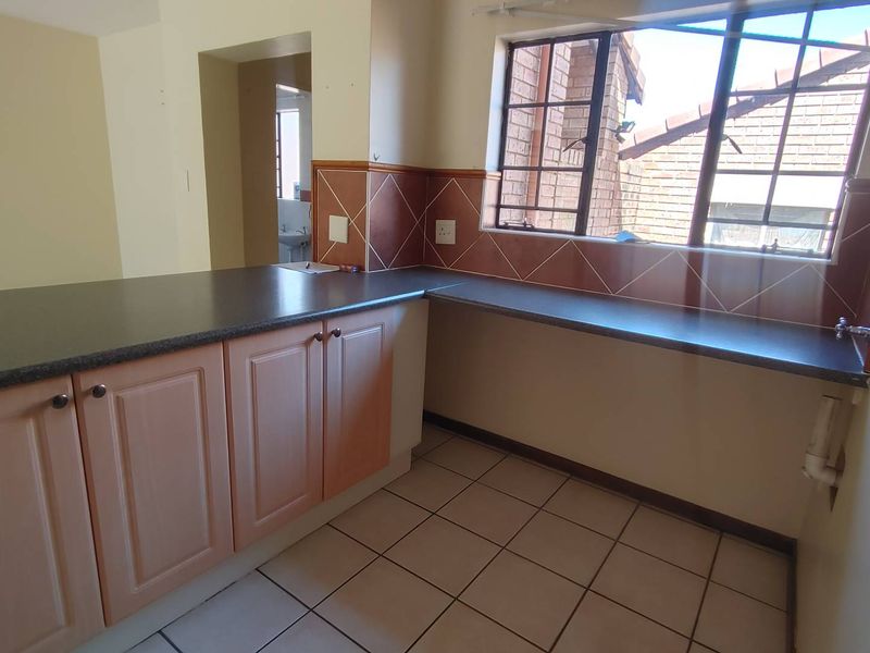 A functional kitchen featuring laminate cabinetry, dark countertops, tiled backsplash, and tiled flooring, offering a clean and empty space ready for updates.