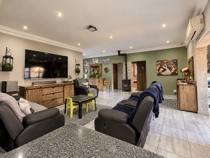 Spacious living room featuring tiled flooring, a wood-burning fireplace, and a wall-mounted air conditioning unit, offering a comfortable and functional family space.