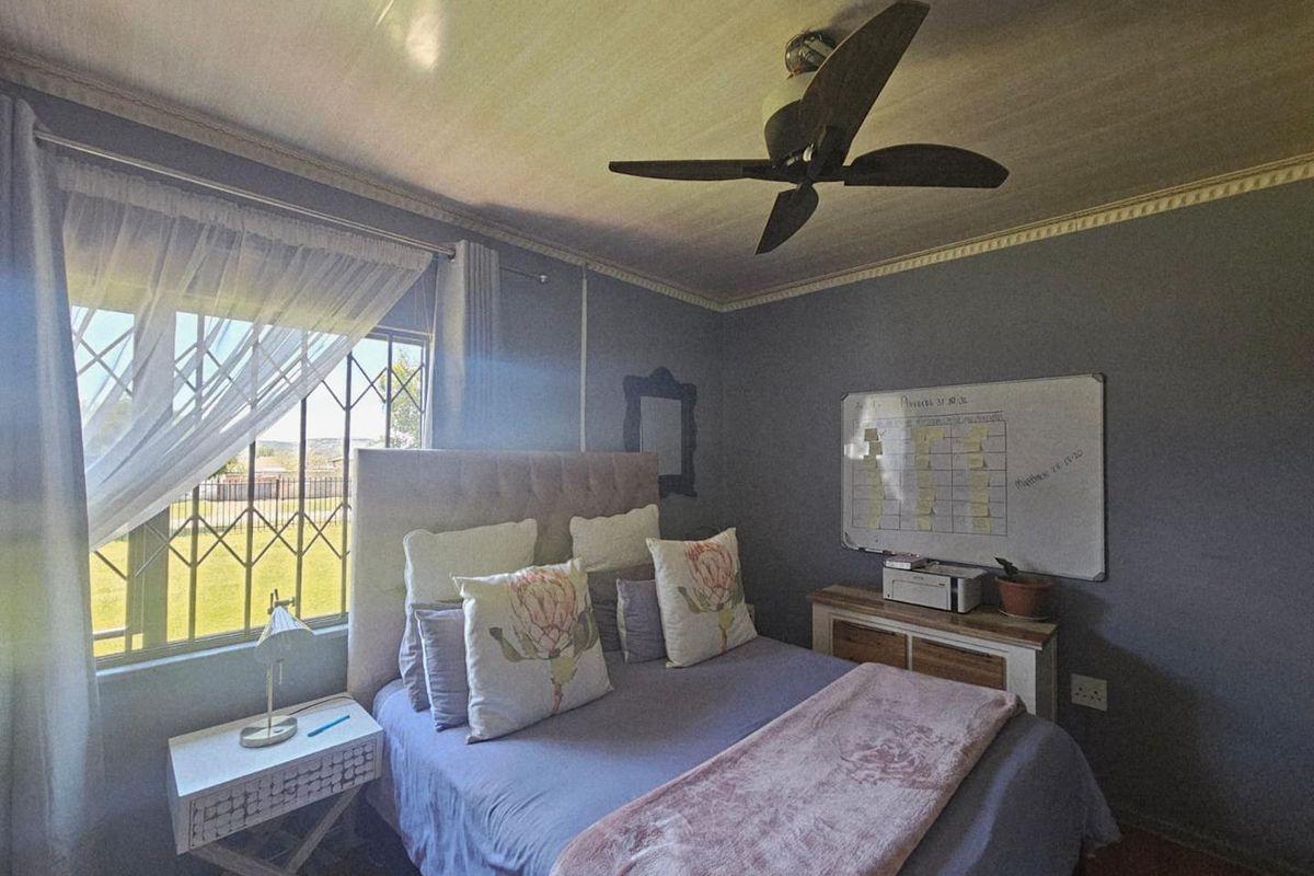 A cozy bedroom featuring a ceiling fan, security bars on the window, and crown molding detail.