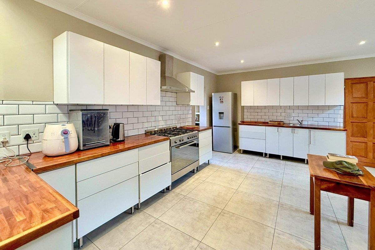 Modern kitchen featuring white cabinetry, wooden countertops, subway tile backsplash, and a stainless steel gas stove with extractor fan.
