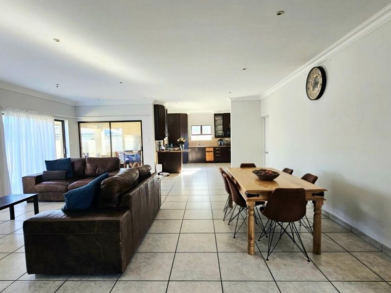 Spacious open-plan living and dining area featuring tiled floors, recessed lighting, and seamless flow to the kitchen and outdoor patio.