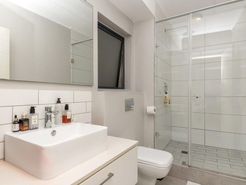 Modern bathroom featuring a vessel sink on a vanity cabinet, a wall-hung toilet, and a spacious walk-in shower with a glass enclosure.