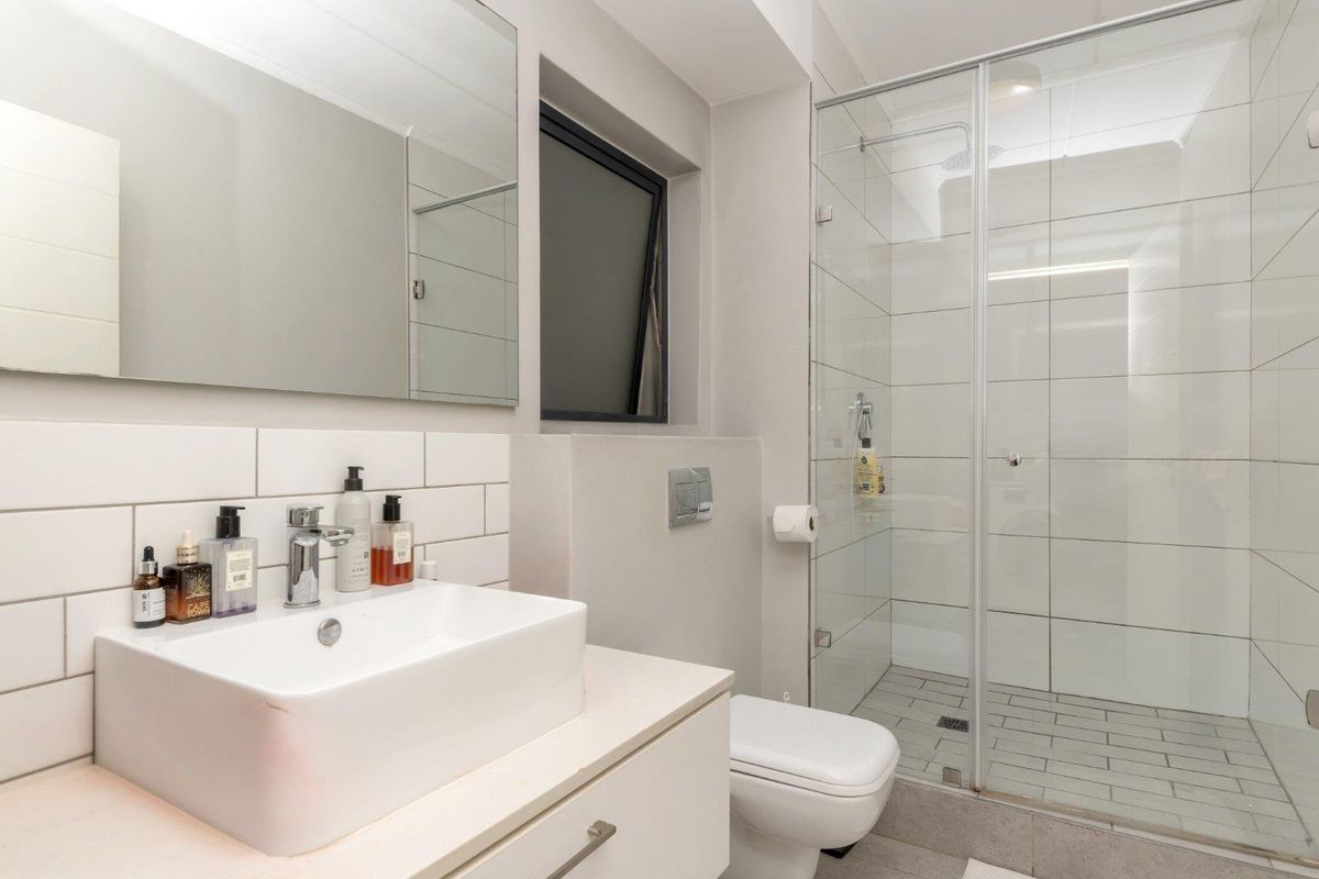 Modern bathroom featuring a vessel sink on a vanity cabinet, a wall-hung toilet, and a spacious walk-in shower with a glass enclosure.