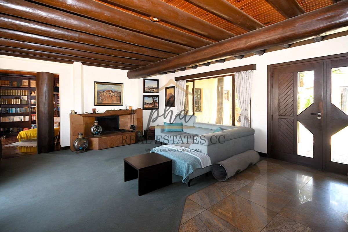 Spacious living room featuring exposed timber beam ceilings, a built-in fireplace, and direct access to the outdoor area through sliding glass doors.