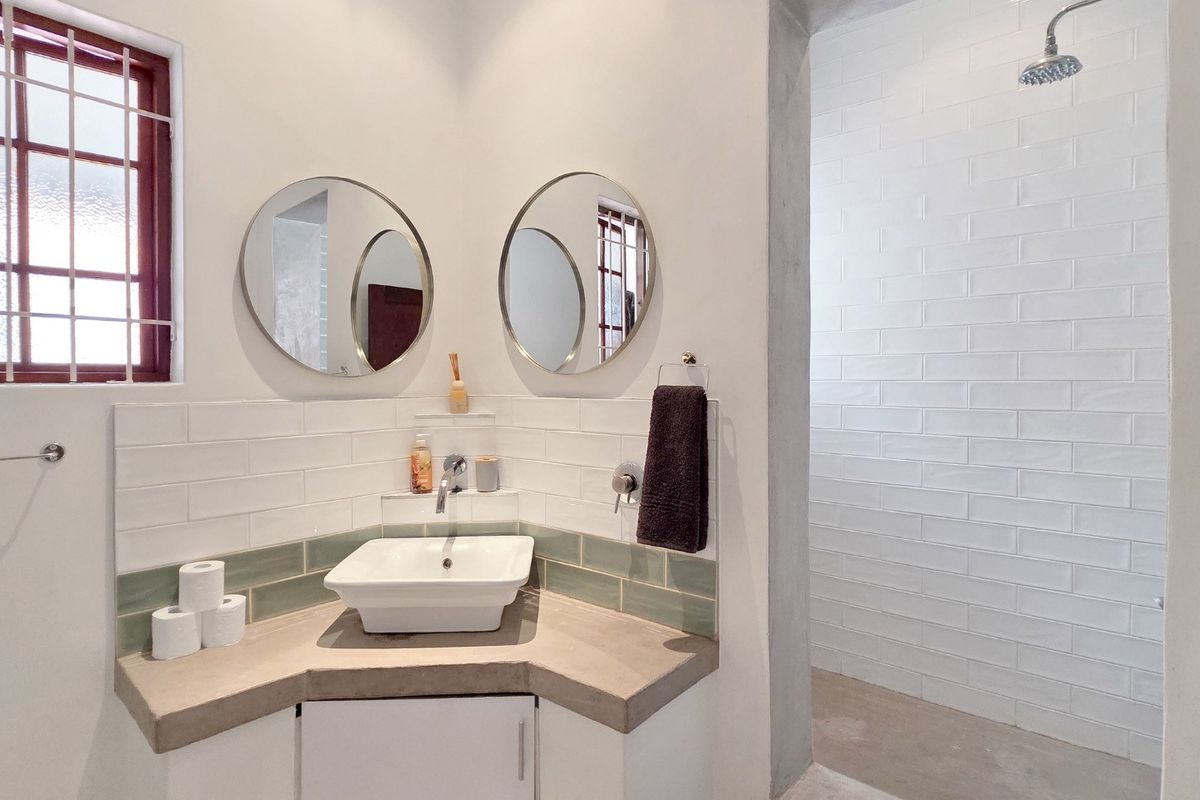 Modern bathroom featuring a corner vanity with a vessel sink, subway tile backsplash, and a spacious walk-in shower with white tiled walls.