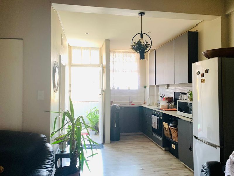Open-plan kitchen area featuring modern dark cabinetry, laminate flooring, and direct access to an outdoor balcony space.