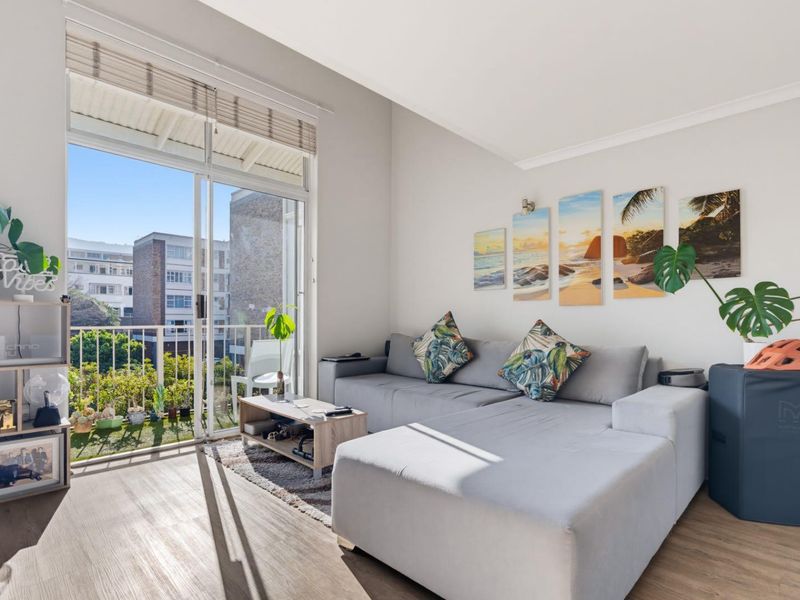 Bright living room featuring laminate flooring and a large sliding glass door providing direct access to a private balcony.