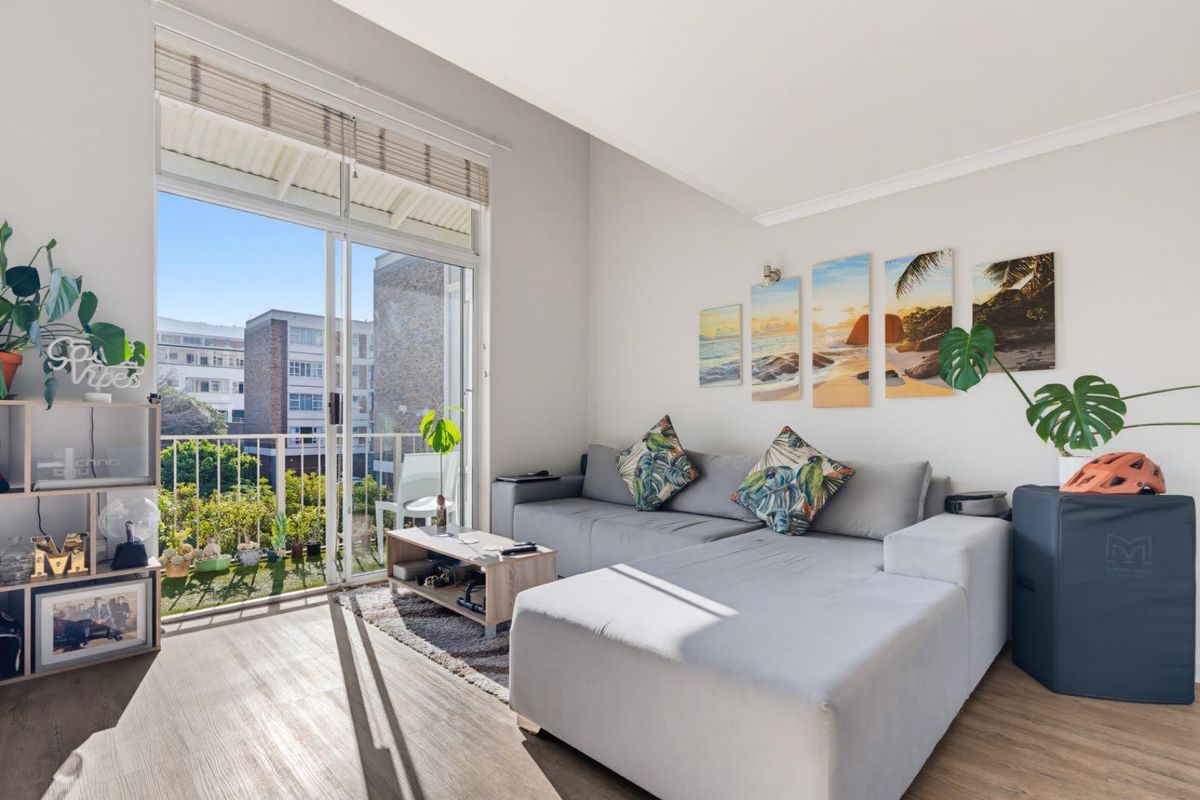Bright living room featuring laminate flooring and a large sliding glass door providing direct access to a private balcony.