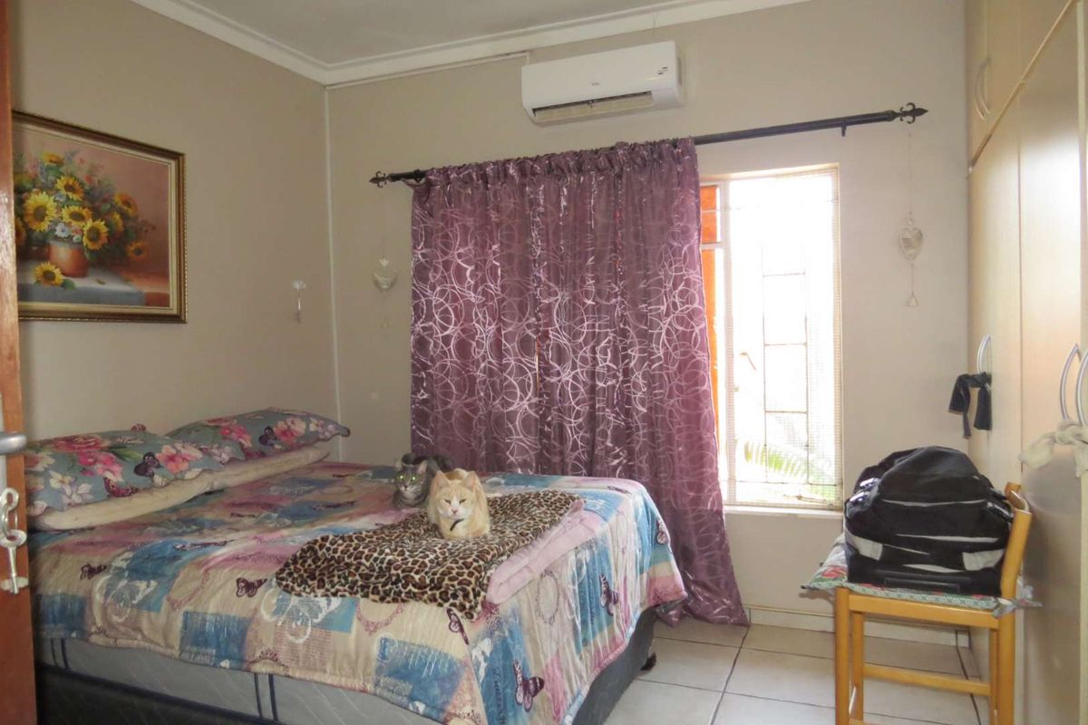 A bedroom featuring tiled flooring, built-in cupboards, and a wall-mounted air conditioning unit.