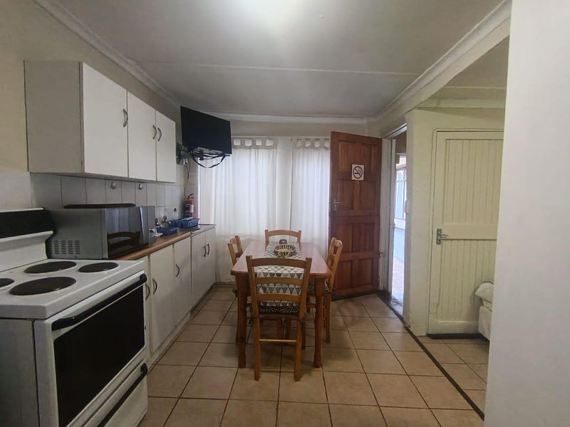 A functional kitchen area featuring tiled flooring, built-in cabinetry, and an electric stove, with direct access to an adjacent room.