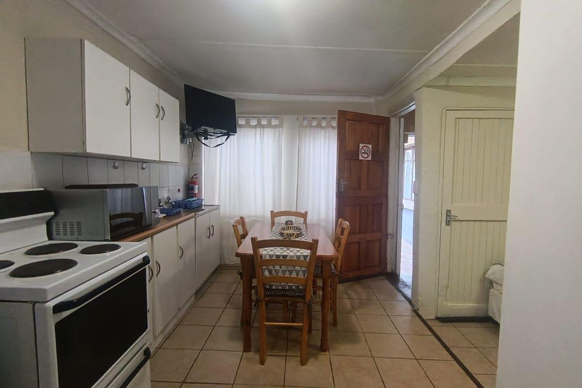 A functional kitchen area featuring tiled flooring, built-in cabinetry, and an electric stove, with direct access to an adjacent room.