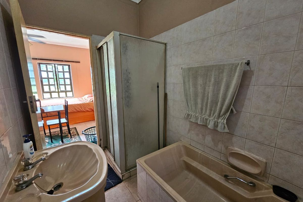 A dated bathroom featuring a built-in bathtub, a separate shower enclosure, and a pedestal basin, with direct access to an adjacent bedroom.