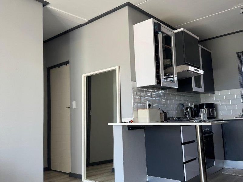 Modern kitchen featuring two-tone cabinetry, subway tile backsplash, built-in oven, extractor fan, and a functional breakfast bar with laminate flooring.