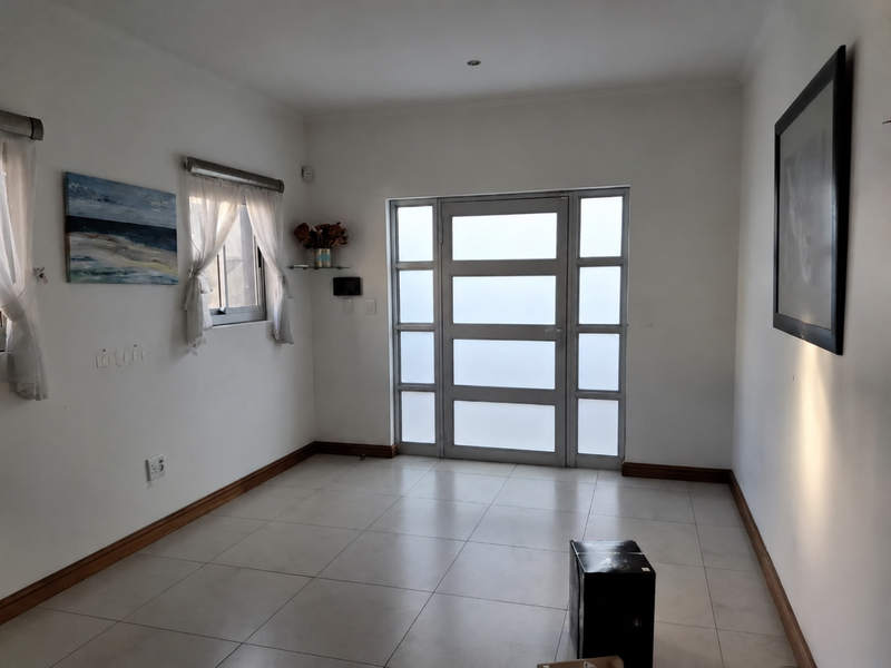 A bright and spacious entrance hall featuring neutral tiled flooring and a modern frosted glass panel front door.