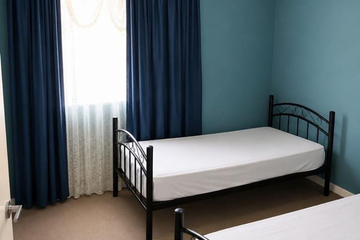 A functional bedroom featuring carpeted flooring and blue painted walls, providing a simple and clean space.