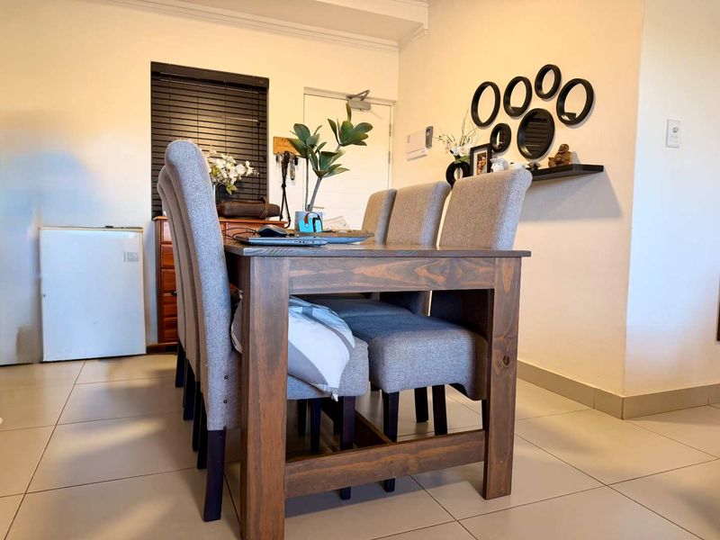 A well-lit dining area featuring neutral tiled flooring and dark venetian blinds, providing a functional and comfortable space for meals.