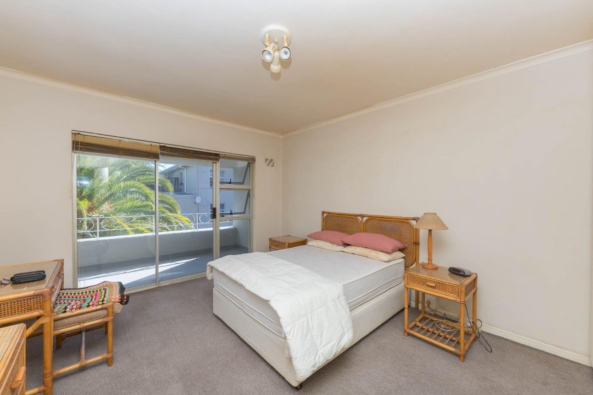 A bedroom featuring carpet flooring, a ceiling light fixture, and a sliding glass door providing access to a balcony.