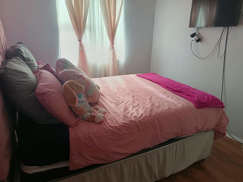 A standard bedroom featuring laminate flooring and a window with installed curtain rails, providing a functional sleeping space.