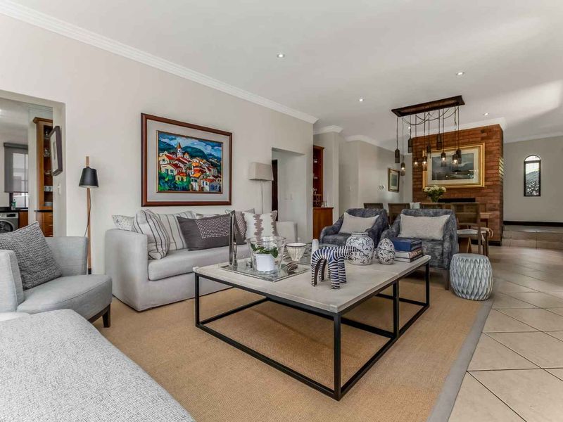 Spacious open-plan living and dining area featuring tiled floors, recessed lighting, and a prominent exposed brick fireplace, creating a warm and inviting atmosphere.