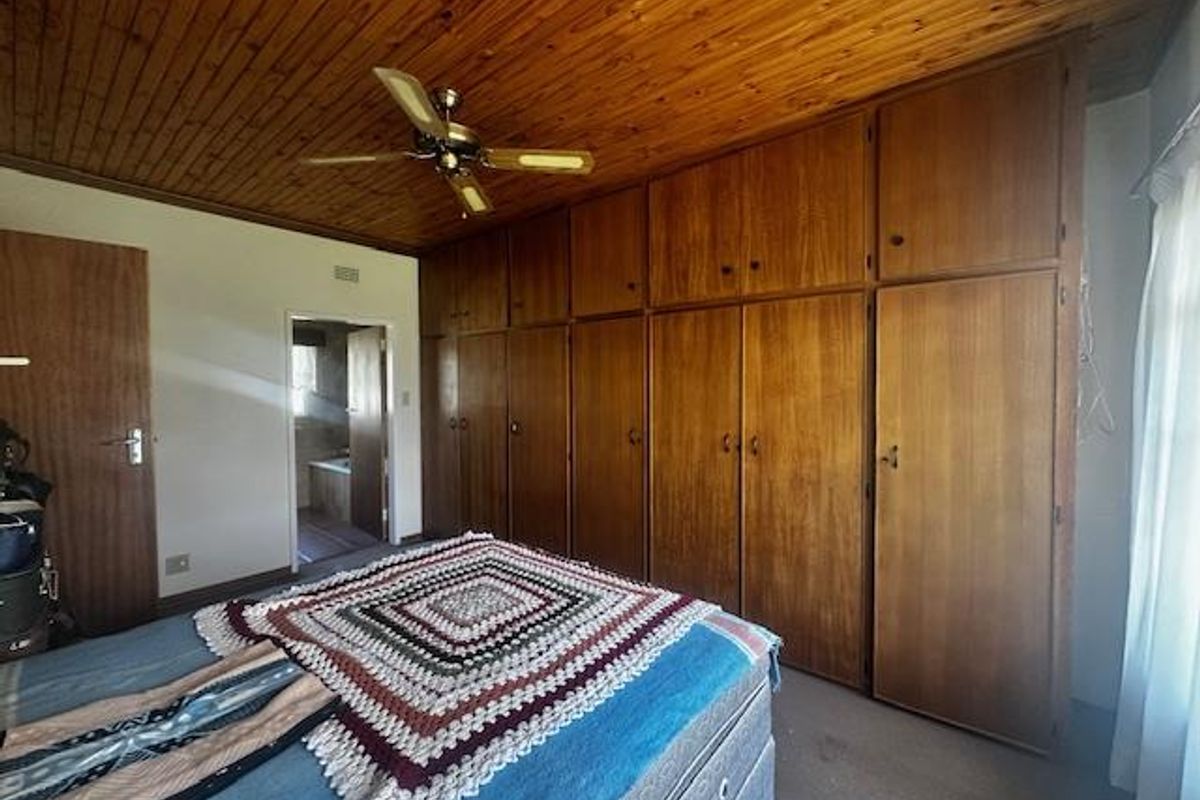 Bedroom featuring extensive floor-to-ceiling built-in wooden cabinetry, a timber-clad ceiling, and a ceiling fan, with an adjoining bathroom visible.