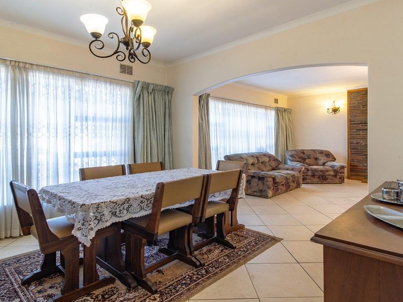 Spacious open-plan dining and living area featuring neutral ceramic floor tiles, an elegant archway, and classic coved cornicing throughout the space.