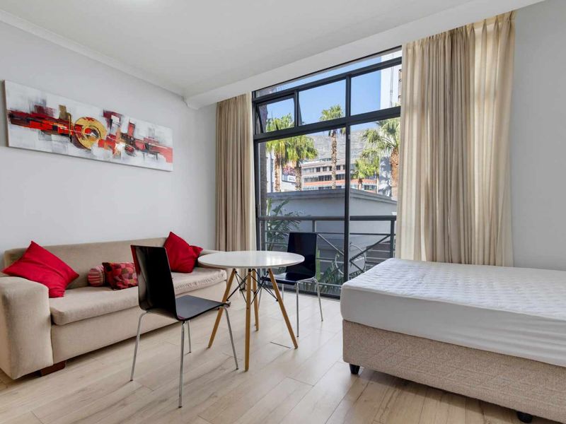 Open plan living area featuring light laminate flooring and a large sliding glass door providing natural light and access to the balcony.