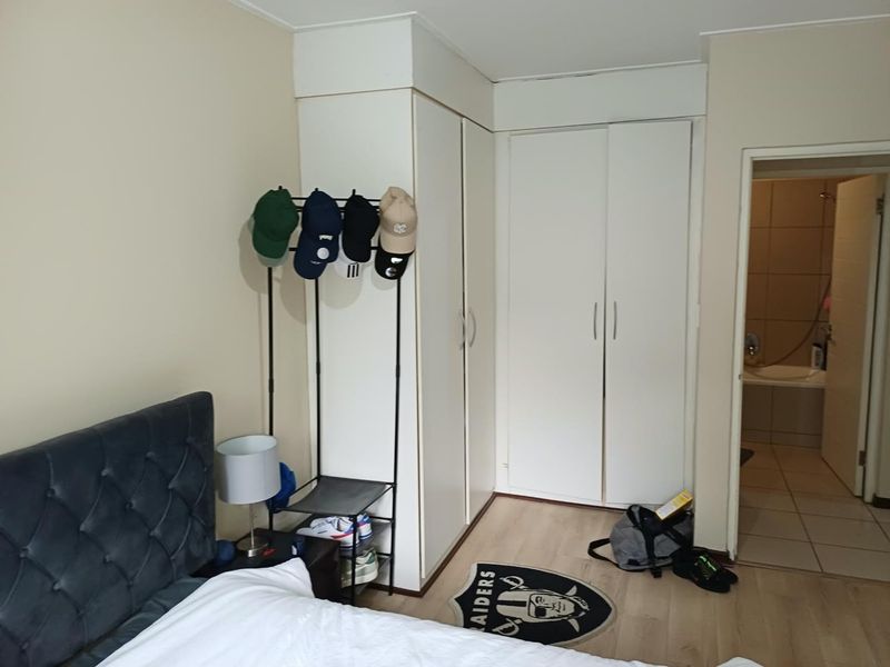 Bedroom featuring built-in cupboards, laminate flooring, and direct access to an en-suite bathroom.