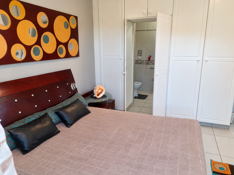 A bedroom featuring built-in cupboards and direct access to an en-suite bathroom with tiled flooring.