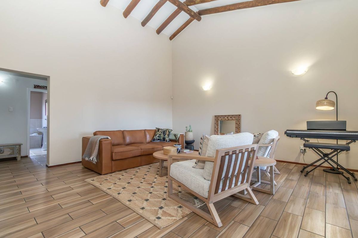 Spacious living area featuring high vaulted ceilings with exposed timber beams and durable wood-look tiled flooring.
