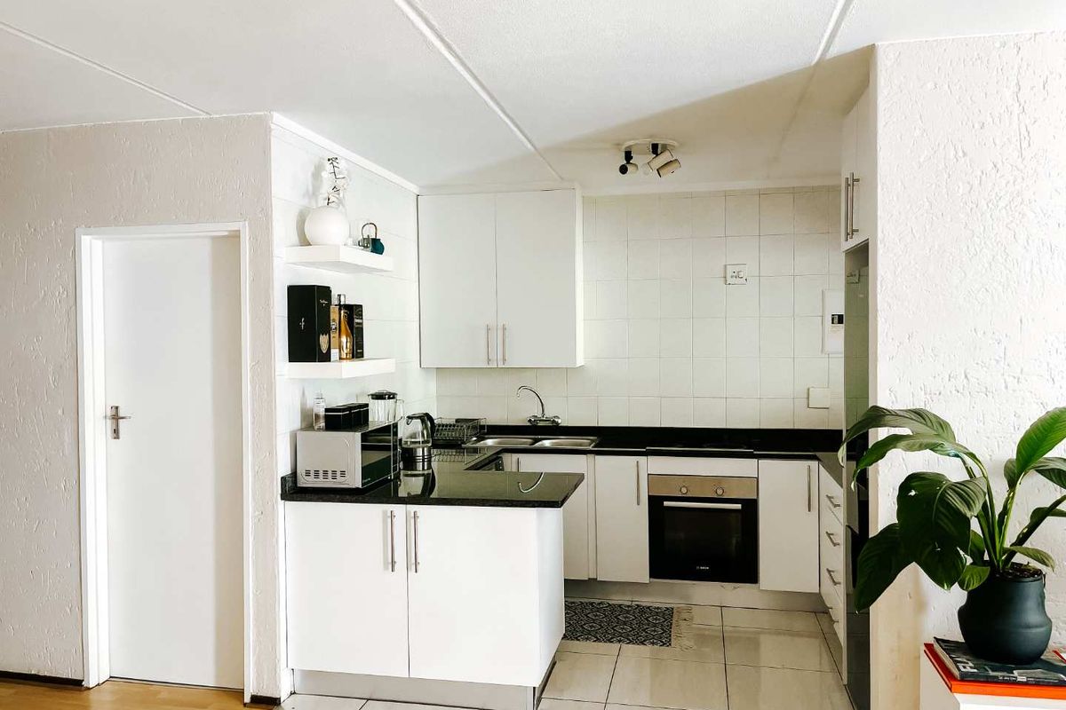 Compact kitchen featuring white cabinetry, black granite countertops, built-in oven, and tiled flooring, offering a functional and efficient workspace.