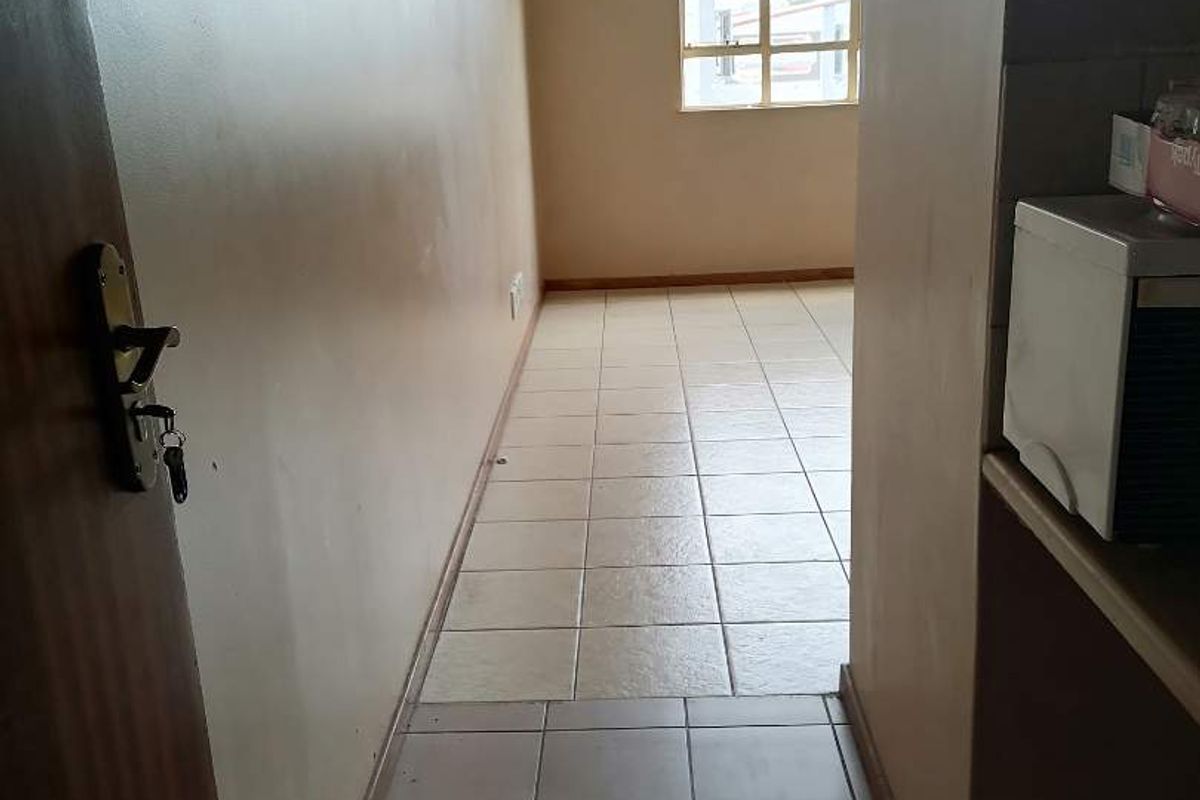 A vacant hallway featuring tiled flooring and a window, providing access to the adjacent living area.
