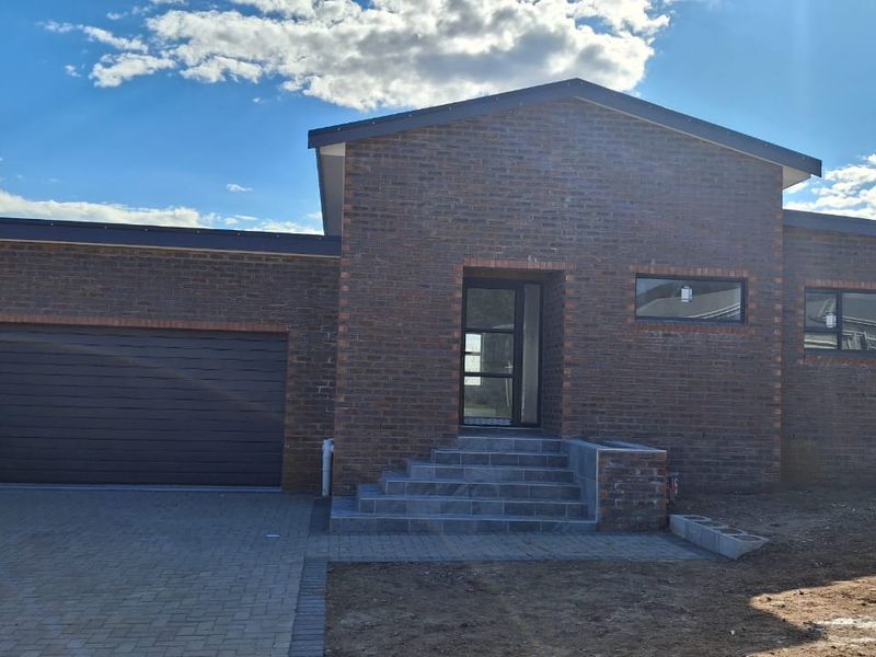 Modern single-story brick home featuring a double garage, paved driveway, and a tiled entrance with contemporary window detailing.