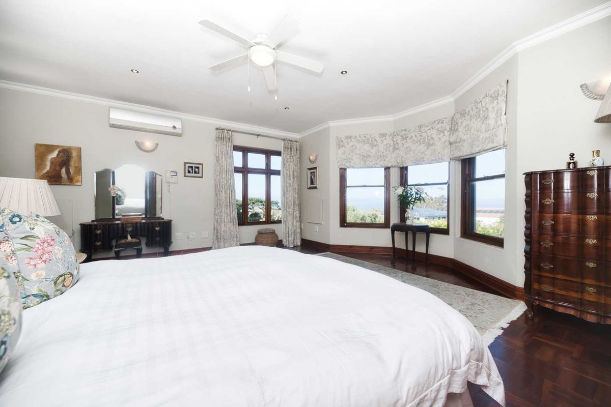 Spacious bedroom featuring hardwood flooring, a ceiling fan, split-system air conditioning, and a large bay window with natural light.